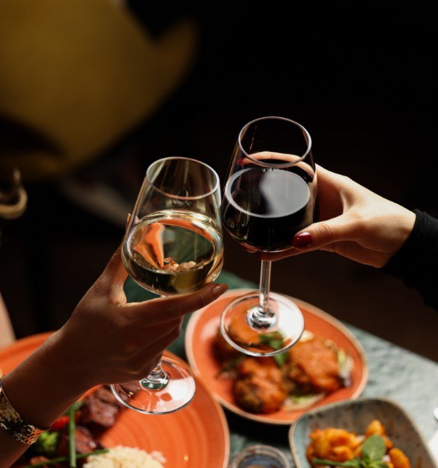 Two glasses of wine raised over a restaurant table