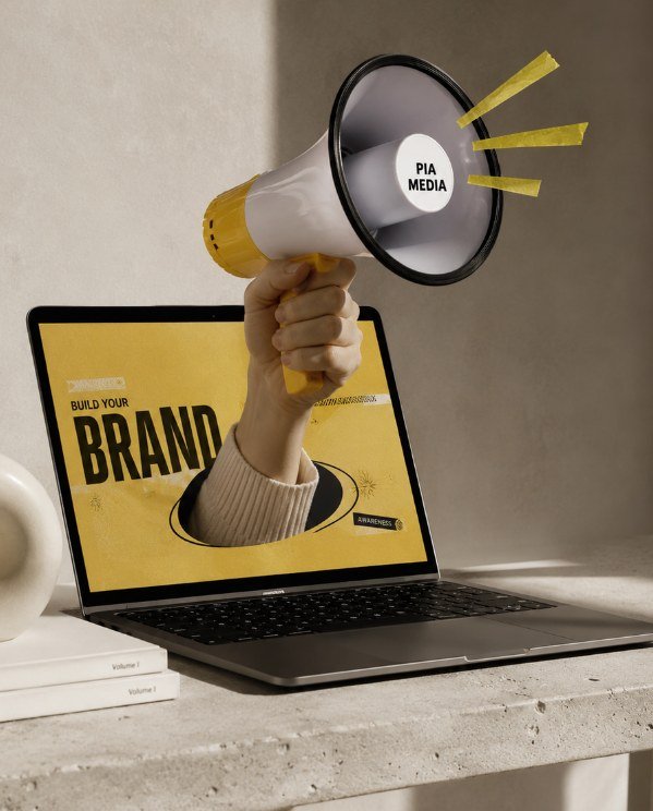 Hand holding a Pia Media megaphone out of a laptop screen